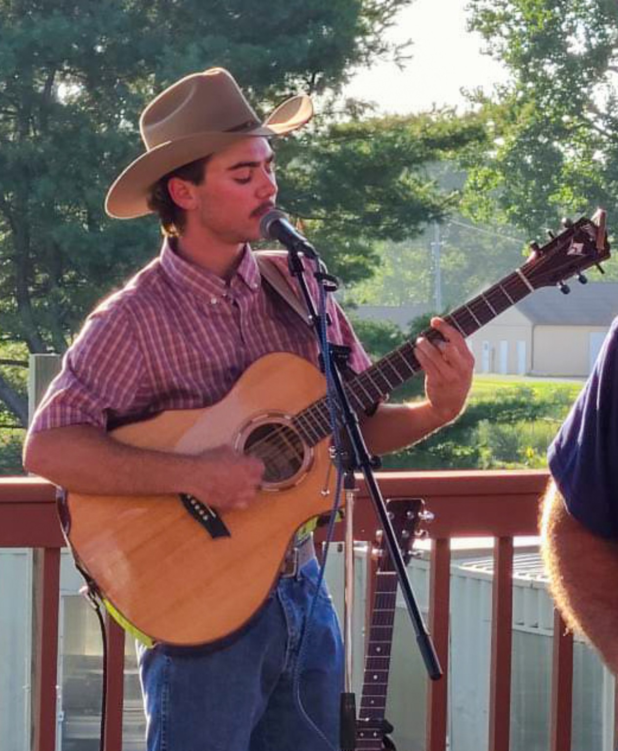 Dylan Soules singing and playing acoustic guitar outdoors